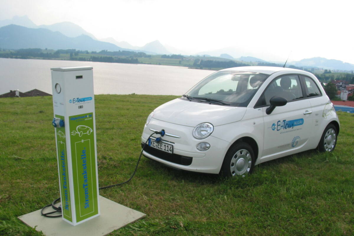 Mobilität - Elektro-Kleinwagen angeschlossen an eine Ladesäule im Grünen