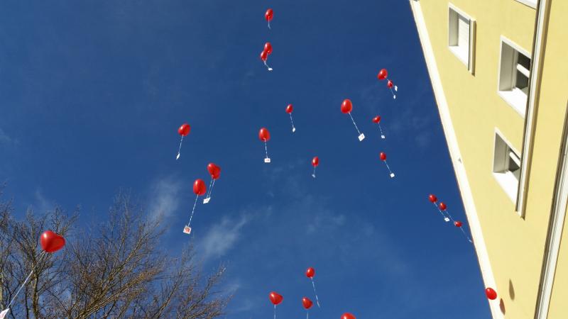 Fliegende rote Luftballons mit Kärtchen